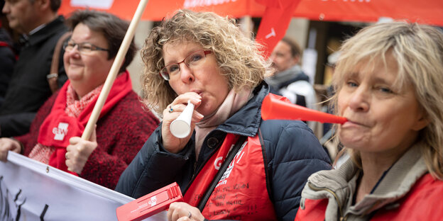 drei erzieherinnen und lehrerinnen mit trillerpfeifen und plakaten bei einem warnstreik während des tarifstreits drei erzieherinnen und lehrerinnen mit trillerpfeifen und plakaten bei einem warnstreik während des tarifstreits