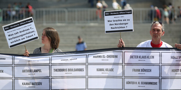 Zwei Personen halten ein Banner mit Todesopfern rechter Gewalt hoch