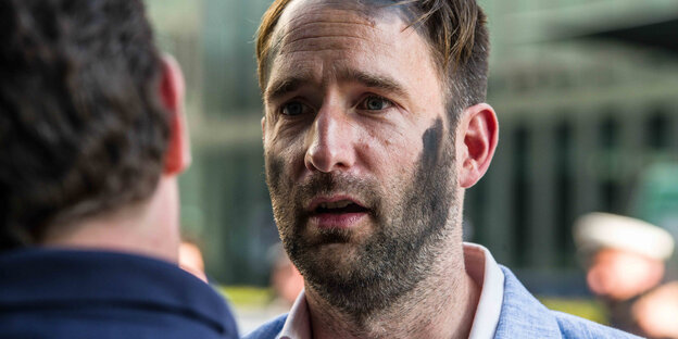 Gesicht von Philipp Ruch, Gründer des Zentrums für politische Schönheit, bei einer Aktion mit schwarzer Farbe auf der Wange Gesicht von Philipp Ruch, Gründer des Zentrums für politische Schönheit, bei einer Aktion mit schwarzer Farbe auf der Wange