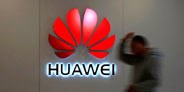 Ein Mann läuft an einem Huawei Logo vorbei Ein Mann läuft an einem Huawei Logo vorbei