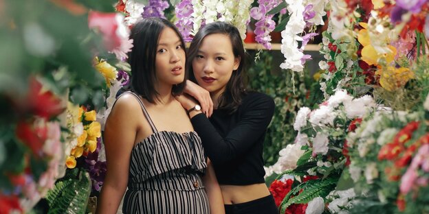 Zwei junge Frauen stehen umringt von Blumen in einem Blumenladen Zwei junge Frauen stehen umringt von Blumen in einem Blumenladen