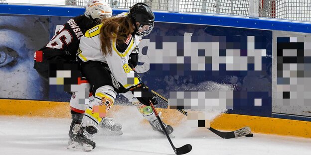 Zwei Eishockey-Spielerinnen im Zweikampf Zwei Eishockey-Spielerinnen im Zweikampf