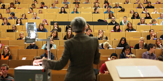 Eine Professorin steht vor einem vollen Hörsaal Eine Professorin steht vor einem vollen Hörsaal