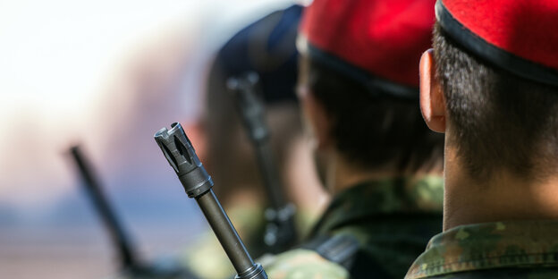 Neben einem uniformierten Bundeswehrsoldaten ist der Mündungslauf einer Waffe zu sehen Neben einem uniformierten Bundeswehrsoldaten ist der Mündungslauf einer Waffe zu sehen