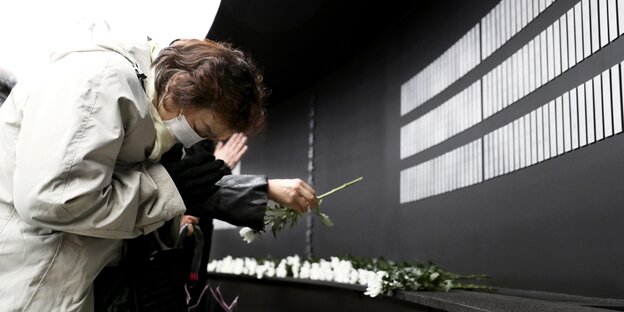 Eine Frau verbeugt sich vor einem Mahnmal Eine Frau verbeugt sich vor einem Mahnmal
