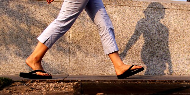 Ein Mensch in grauer wadenlager Hose und schwarzen Flip Flops Ein Mensch in grauer wadenlager Hose und schwarzen Flip Flops