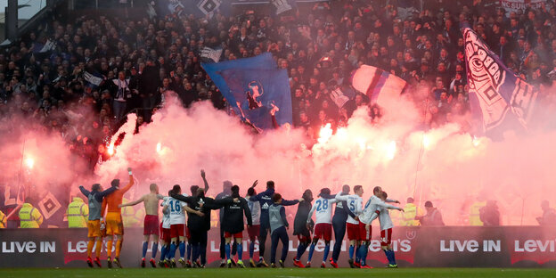 Die Spiler des HSV lassen sich von Fans mit bengalischen Feuern feiern. Die Spiler des HSV lassen sich von Fans mit bengalischen Feuern feiern.