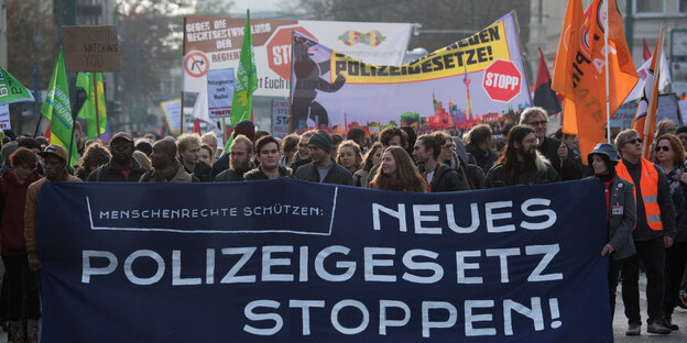 Demonstration gegen das Polizeigesetz: Demonstrantinnen und Demonstranten halten Banner und Fahnen und marschieren auf der Straße