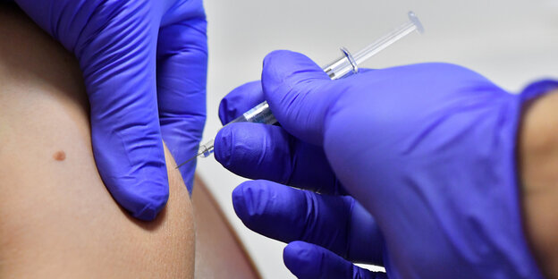 Eine Person wird in mit einer Impfspritze in den Arm gestochen Eine Person wird in mit einer Impfspritze in den Arm gestochen