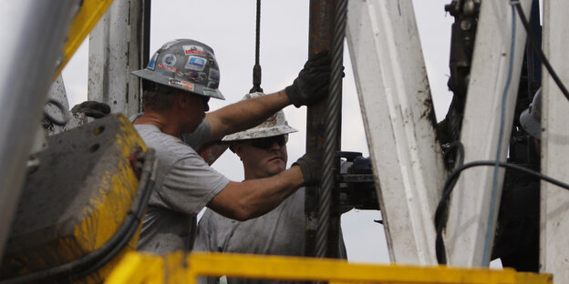 Arbeiter mit Helmen auf einem Bohrturm Arbeiter mit Helmen auf einem Bohrturm