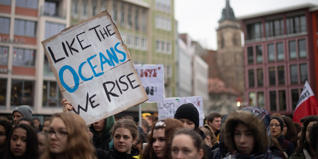 Eine Teilnehmerin hält während der Klimaschutz-Demonstration «Fridays for Future» ein Schild hoch, auf dem «Like the oceans we rise» steht