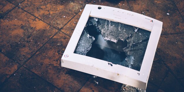 Ein zerschmetterter PC-Bildschirm liegt auf dem Boden Ein zerschmetterter PC-Bildschirm liegt auf dem Boden