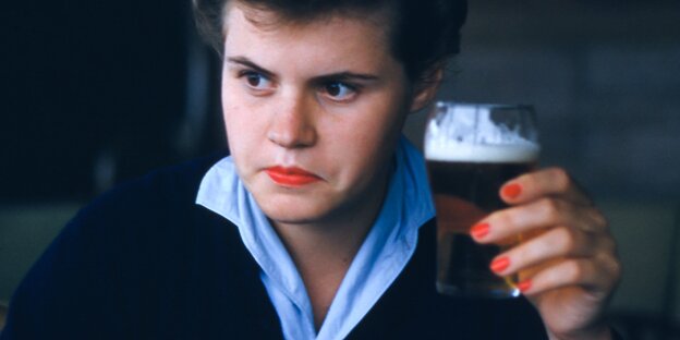 Eine Frau mit Bierglas in der Hand schaut entschlossen Eine Frau mit Bierglas in der Hand schaut entschlossen