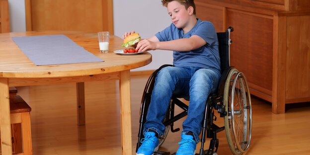 Ein Junge im Rollstuhl an einem Tisch Ein Junge im Rollstuhl an einem Tisch
