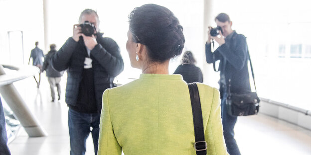 Sahra Wagenknecht mit dem Rücken zur Kamera läuft einen Gang hinunter und wird von der Presse fotografiert. Sahra Wagenknecht mit dem Rücken zur Kamera läuft einen Gang hinunter und wird von der Presse fotografiert.