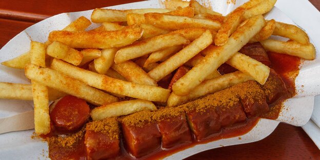 Eine Currywurst mit Pommes frites liegt in einer Schale Eine Currywurst mit Pommes frites liegt in einer Schale