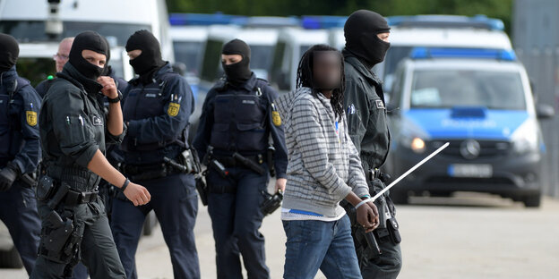 Polizisten führen einen gefesselten Mann ab Polizisten führen einen gefesselten Mann ab