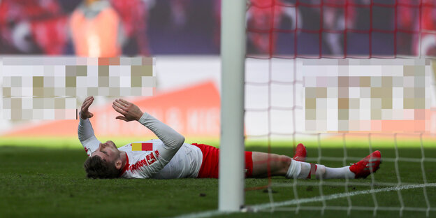 Fußballspieler Timo Werner liegt nach einem Fehlschuss auf dem Rasen vor dem Tor und hebt die Arme in die Luft Fußballspieler Timo Werner liegt nach einem Fehlschuss auf dem Rasen vor dem Tor und hebt die Arme in die Luft