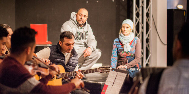 Auf einer Bühne sitzen Musiker, einer mit Gitarre und spielen. Auf einer Bühne sitzen Musiker, einer mit Gitarre und spielen.