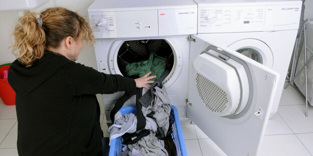 eine Frau kniet vor einem Wäschetrockner eine Frau kniet vor einem Wäschetrockner