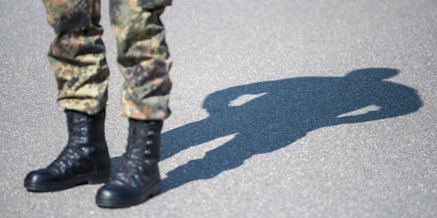 Ein Bundeswehrsoldat steht, man sieht nur seine Beine und seinen Schatten Ein Bundeswehrsoldat steht, man sieht nur seine Beine und seinen Schatten