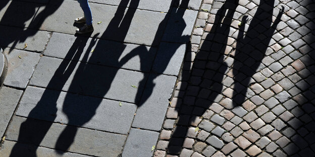 Eine Familie wirft lange Schatten auf Kopfsteinpflaster Eine Familie wirft lange Schatten auf Kopfsteinpflaster
