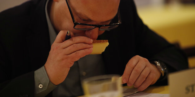 Ein Mann riecht an einem Stück Käse Ein Mann riecht an einem Stück Käse