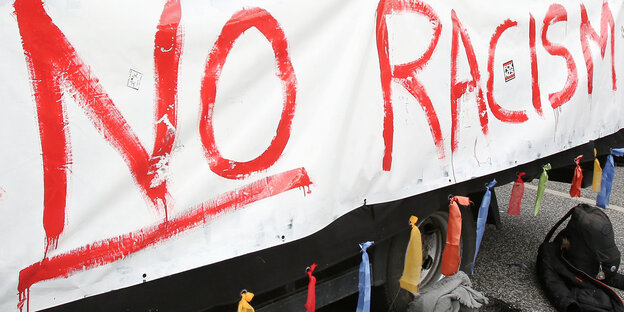 „No racism“ steht bei einer Parade gegen Rassismus an einem Wagen. „No racism“ steht bei einer Parade gegen Rassismus an einem Wagen.