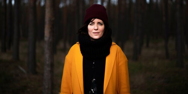 Sarah Kuttner mit Mütze und in gelber Jacke in einem Wald Sarah Kuttner mit Mütze und in gelber Jacke in einem Wald
