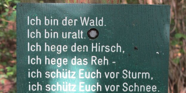 Ein Schild mit Aufschrift, an einem Baum befestigt Ein Schild mit Aufschrift, an einem Baum befestigt