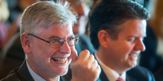 Ein Mann mit grauen Haaren lacht und zeigt seinen Daumen Ein Mann mit grauen Haaren lacht und zeigt seinen Daumen