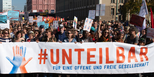 Menschen hinter einem #unteilbar-Transparent auf einer Demo in Berlin Menschen hinter einem #unteilbar-Transparent auf einer Demo in Berlin