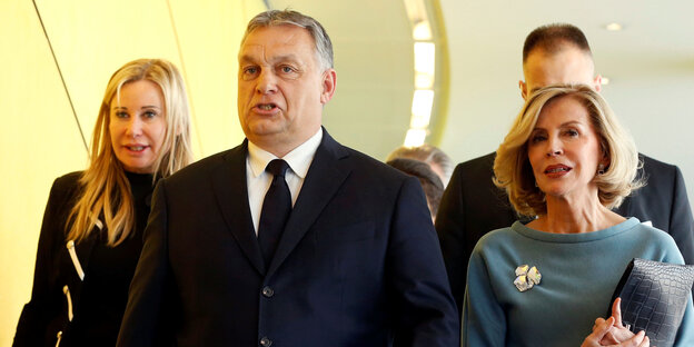 Viktor Orban, ein Mann in Anzug und Krawatte, rechts und links von ihm sind Frauen zu sehen Viktor Orban, ein Mann in Anzug und Krawatte, rechts und links von ihm sind Frauen zu sehen