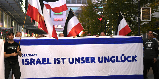 Demonstranten zeigen schwarz-weiß-rote Fahnen und ein Transparent mit der Aufschrift "Der Staat Israel ist unser Unglück" Demonstranten zeigen schwarz-weiß-rote Fahnen und ein Transparent mit der Aufschrift "Der Staat Israel ist unser Unglück"