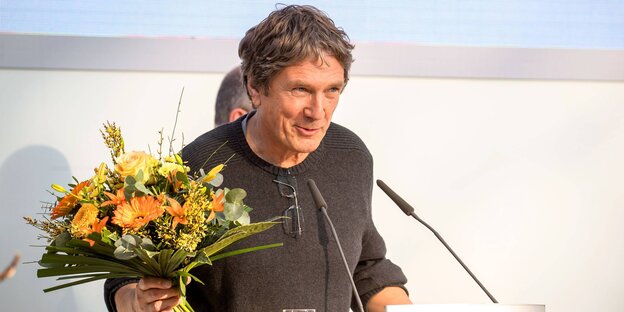 Autor Harald Jähner mit Blumen in der Hand auf der Bühne Autor Harald Jähner mit Blumen in der Hand auf der Bühne