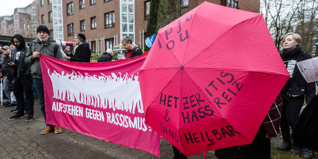 Eein Frau hält einen Regenschirm mit der Aufschrift "Hetzeritis & Hassreiz sind heilbar" Eein Frau hält einen Regenschirm mit der Aufschrift "Hetzeritis & Hassreiz sind heilbar"