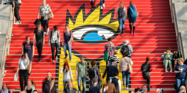 Menschen gehen eine bunt bemalte Treppe hinauf Menschen gehen eine bunt bemalte Treppe hinauf