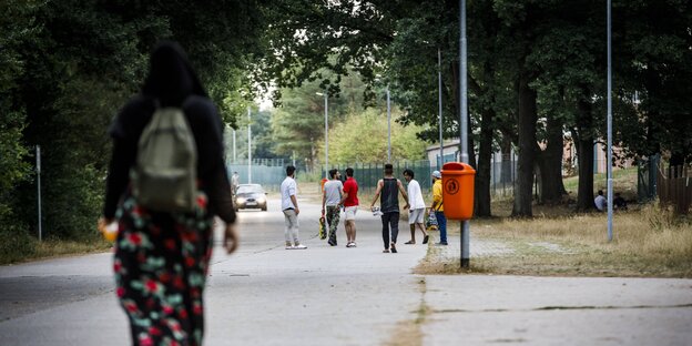 Bewohner einer Erstaufnahmeeinrichtung für Asylsuchende laufen auf der Straße Bewohner einer Erstaufnahmeeinrichtung für Asylsuchende laufen auf der Straße
