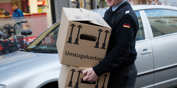 Ein Mann trägt zwei Umzugskartons Ein Mann trägt zwei Umzugskartons