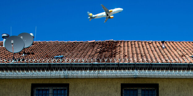 Ein Flugzeug fliegt über einem Gebäudekomplex, der der Unterbringung von Asylbewerbern in Abschiebungshaft dient. Ein Flugzeug fliegt über einem Gebäudekomplex, der der Unterbringung von Asylbewerbern in Abschiebungshaft dient.