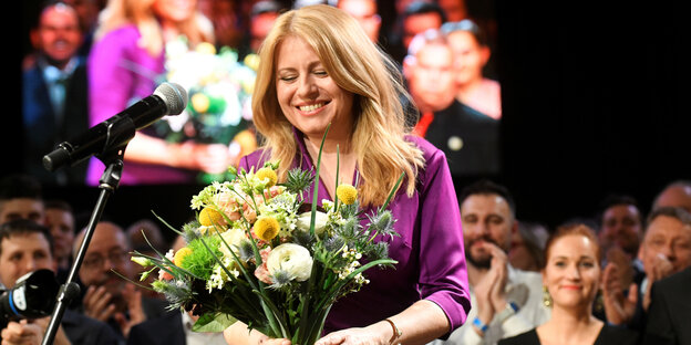 Zuzana Caputova steht lächelnd auf einer Bühne, in den Händen ein Blumenstrauß. Zuzana Caputova steht lächelnd auf einer Bühne, in den Händen ein Blumenstrauß.
