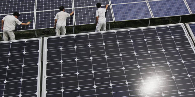 drei Männer polieren große Solarmodule drei Männer polieren große Solarmodule