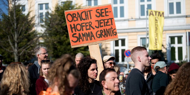 Menschen auf einer Demo, einer trägt ein Schid, auf den steht „Obacht Seehofer jetzt sammer grantig“ Menschen auf einer Demo, einer trägt ein Schid, auf den steht „Obacht Seehofer jetzt sammer grantig“