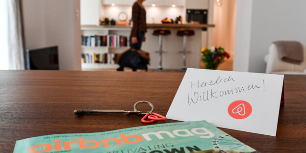 Ein Schlüssel mit einem Airbnb-Anhäger, ein Airbnbmag-Magazin und eine Herzlich-Willkommen-Karte liegen in der Wohnung eines Airbnb-Gastgebers Ein Schlüssel mit einem Airbnb-Anhäger, ein Airbnbmag-Magazin und eine Herzlich-Willkommen-Karte liegen in der Wohnung eines Airbnb-Gastgebers
