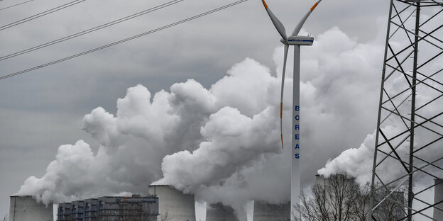 Ein Windrad vor einem Kohlekraftwerk