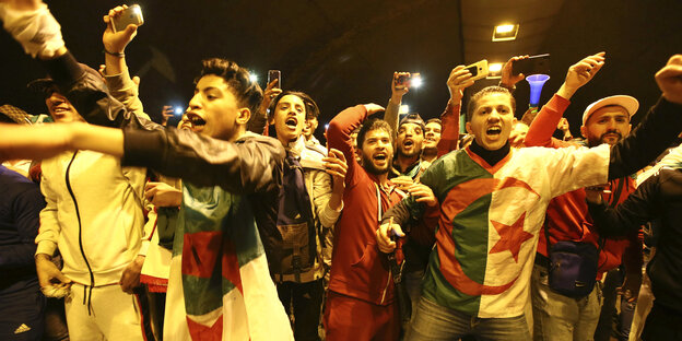 Menschen mit Algerienfahnen stehen eng zusammen und jubeln Menschen mit Algerienfahnen stehen eng zusammen und jubeln