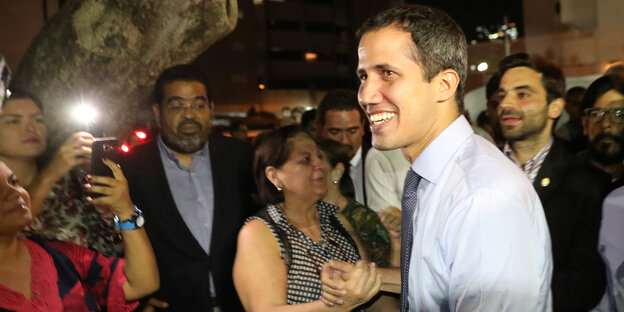 Juan Guaidó begrüßt eine Frau und wird von umstehenden Menschen angelächelt Juan Guaidó begrüßt eine Frau und wird von umstehenden Menschen angelächelt