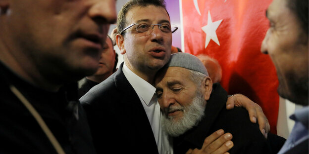 Imamoglu nimmt einen älteren Herrn in den Arm. Im Hintergrund eine türkische Flagge. Imamoglu nimmt einen älteren Herrn in den Arm. Im Hintergrund eine türkische Flagge.