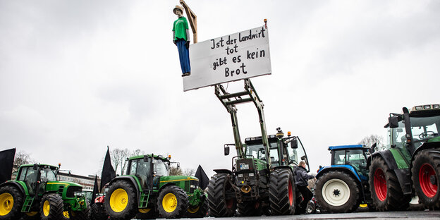 Eine Puppe hängt an einem Traktor und baumelt an einem Galgen mit dem Schild: "Ist der Landwirt tot gibt es kein Brot". Eine Puppe hängt an einem Traktor und baumelt an einem Galgen mit dem Schild: "Ist der Landwirt tot gibt es kein Brot".