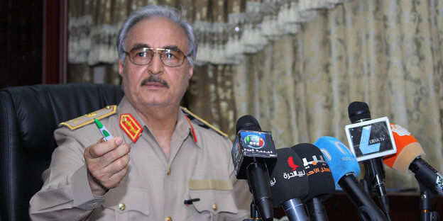 Khalifa Haftar vor Mikrofonen. In der Hand hält er einen Kugelschreiber. Khalifa Haftar vor Mikrofonen. In der Hand hält er einen Kugelschreiber.